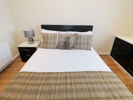 A bedroom with a bed with plaid cushions and a blanket a bedside table with a lamp and a set of drawers at Walworth Castle Lodge in Walworth near Darlington