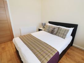 A bedroom with a double bed with plaid cushions and runner wooden floor and a bedside table with a lamp at Walworth Castle Lodge in Walworth near Darlington