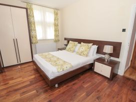 A bedroom with a bed with floral pillows and runner a wardrobe a nightstand with a lamp and wood flooring at Walworth Castle Lodge Walworth near Darlington