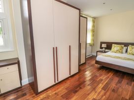 A bedroom with wooden floor a bed with yellow pillows a wardrobe and a nightstand with a lamp at Walworth Castle Lodge Walworth near Darlington