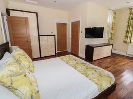 A bedroom with a bed yellow floral pillows wooden doors a wall-mounted television and wooden floor at Walworth Castle Lodge in Walworth near Darlington