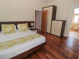 A bedroom with a bed and bedside table with lamp a wardrobe and chest of drawers wooden floor and an open door showing a bathroom at Walworth Castle Lodge in Walworth near Darlington
