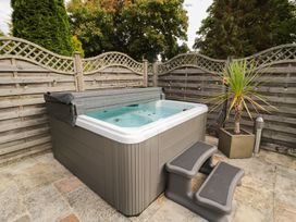 An outdoor hot tub with steps near a wooden fence and a potted plant at Walworth Castle Lodge in Walworth near Darlington