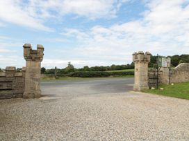 A gravel driveway entrance with stone pillars and a road beyond at Walworth Castle Lodge in Walworth near Darlington