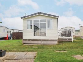 A row of mobile homes with a lawn and paved path at Plot LD19 in Heysham