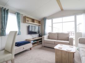 A living room with sofas a coffee table a television and blue curtains at Plot LD19 in Heysham