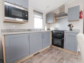 A kitchen with grey cabinets a black oven a microwave a kettle and a toaster at Plot LD19 in Heysham