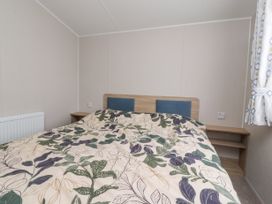 A bedroom with a double bed covered with floral bedding and two bedside tables at Plot LD19 Heysham