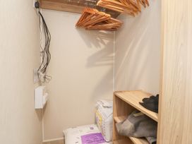 A closet with wooden hangers on a rod shelves with folded clothes and bedding at Plot LD19 in Heysham