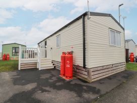 A mobile home with white steps and railing outside next to red gas cylinders on a paved area at Plot LD19 in Heysham