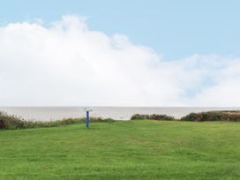 A grassy area with a small informational sign and a body of water in the background at Plot LD19 in Heysham