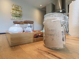 A kitchen countertop with a jar labeled Doggy Treats a wooden tray with containers and paper towels at 1 Kessingland Cottages in Kessingland