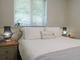 A bedroom with a bed in white linens two bedside tables with lamps and small plants at 1 Kessingland Cottages in Kessingland