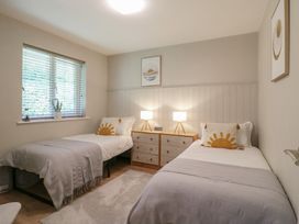 A bedroom with two single beds a window with blinds and a wooden dresser with two lamps at 1 Kessingland Cottages in Kessingland