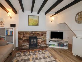 A living room with a fireplace, sofa, and television at Honeysuckle Cottage in Charlestown