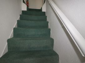 A staircase with green carpet and a handrail at Honeysuckle Cottage in Charlestown