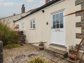 An entrance of a cottage with a white door and plants at Honeysuckle Cottage in Charlestown