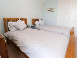 A bedroom with two single wooden beds with white bedding and pillows at Flat 3 in Trearddur Bay
