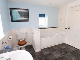 A bathroom with a bathtub toilet a sink a window and cabinets at Flat 3 in Trearddur Bay