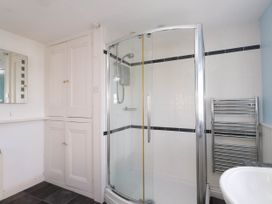 A bathroom with a corner shower enclosure towel radiator storage cupboards and a sink at Flat 3 in Trearddur Bay