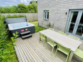 A garden with a hot tub and dining furniture at Una, Lodge 73 Carbis Bay