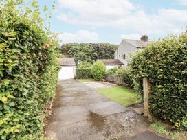A pathway leading to a garage and house with hedges at Driftwood