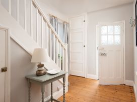 A hallway with stairs and a table with a lamp at Driftwood in Embleton