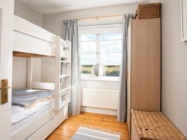 A bedroom with a bunk bed and window at Driftwood in Embleton