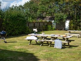 A garden with picnic tables and a barbecue at Driftwood in Embleton