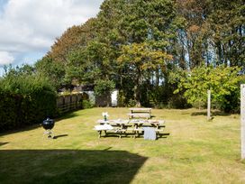 A garden with a picnic table and barbecue grill at Driftwood in Embleton