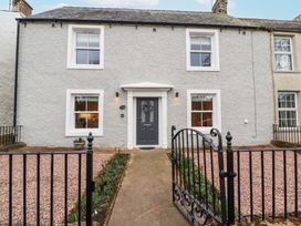 A house with a dark grey front door and four windows surrounded by a black metal gate at 1 Brookside in Warcop