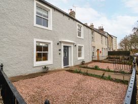 Exterior of a row of houses with gravel gardens and metal gates at 1 Brookside in Warcop
