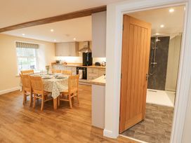 A kitchen with a dining table and chairs and an open door revealing a shower room at 1 Brookside in Warcop