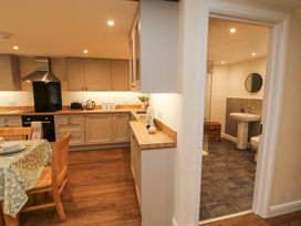 A kitchen with dining table and chairs next to a bathroom with sink toilet and mirror at 1 Brookside Warcop