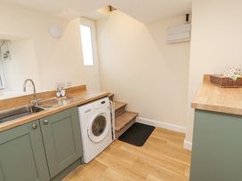 A utility room with a washing machine under a countertop and stairs leading up at 1 Brookside in Warcop