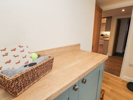 A countertop with a basket containing a tennis ball and a patterned item in a room with an open door leading to a kitchen at 1 Brookside in Warcop