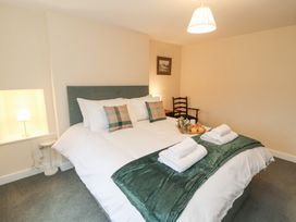 A bedroom with a double bed with towels and a tray on it a chair and lamp at 1 Brookside Warcop