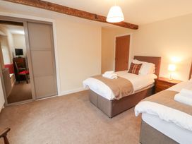 A bedroom with two single beds side by side with folded towels and pillows and a bedside table with a lamp at 1 Brookside in Warcop