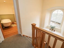 A staircase with wooden handrails next to a bathroom with a freestanding bathtub and wooden floor at 1 Brookside in Warcop
