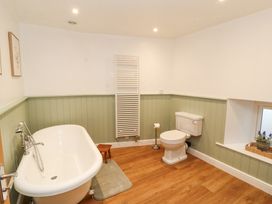 A bathroom with a bathtub a toilet a towel radiator and a window with a plant at 1 Brookside in Warcop