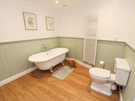 A bathroom with a freestanding bathtub toilet two framed pictures and a towel radiator at 1 Brookside in Warcop