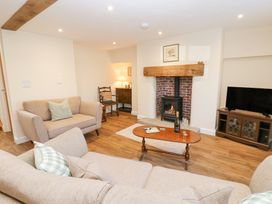 A living room with sofas a wooden coffee table a fireplace and a television at 1 Brookside in Warcop