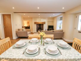 A dining table set for six in an open plan living room with sofas and a fireplace at 1 Brookside in Warcop