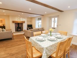 A dining table set for six adjacent to a living area with sofas and a fireplace at 1 Brookside in Warcop