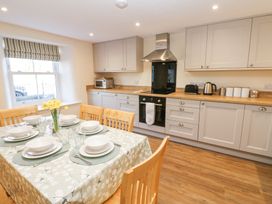 A kitchen and dining area with a table set for six and wooden chairs at 1 Brookside in Warcop