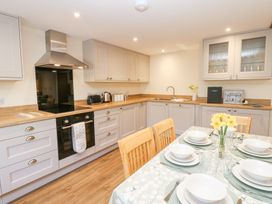 A kitchen with built in oven hob and hood and a dining table set with plates bowls and glasses at 1 Brookside in Warcop