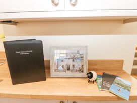 A counter with a guest information folder a framed picture of a house a toy sheep and several brochures at 1 Brookside in Warcop