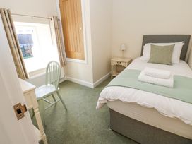 A small bedroom with a single bed bedside table and lamp a chair and desk near a window at 1 Brookside in Warcop