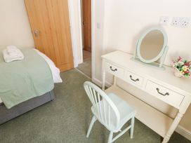 A bedroom with a bed and a dressing table with a chair and a mirror at 1 Brookside in Warcop