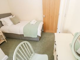 A bedroom with a single bed a wooden door a white desk with a mirror and a chair at 1 Brookside in Warcop